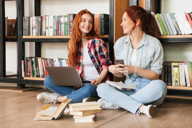 Dos lindas chicas adolescentes sentadas en el suelo