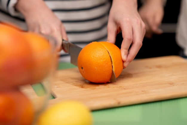 Dos lindas chicas hermanas están haciendo jugo de naranja fresco Manos primer plano Familia Fruta fresca