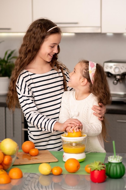 Dos lindas hermanas están haciendo jugo de naranja fresco Familia Fruta fresca Alimentación saludable