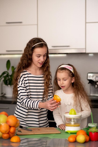 Dos lindas hermanas están haciendo jugo de naranja fresco Familia Fruta fresca Alimentación saludable