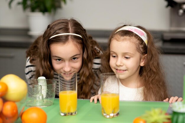 Dos lindas hermanas están haciendo jugo de naranja fresco Fruta fresca Alimentación saludable