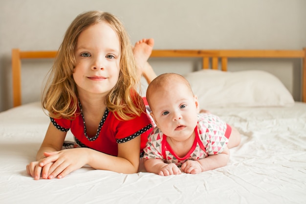 Dos lindas hermanas: la mayor y la menor, están acostadas en la cama