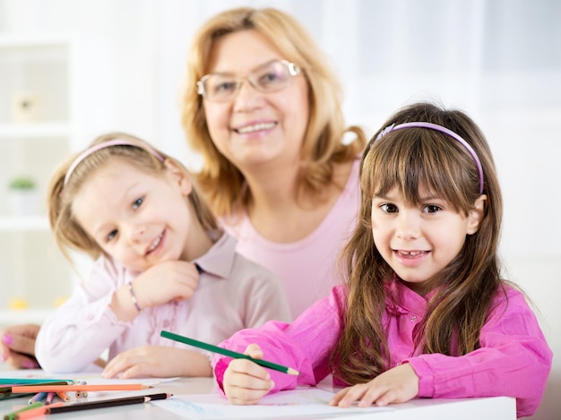 Dos lindas niñas dibujando con lápices de colores en casa con la abuela