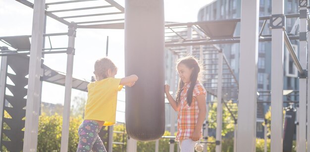 Dos lindas niñas divirtiéndose en un patio de recreo al aire libre en verano. actividades deportivas para niños.