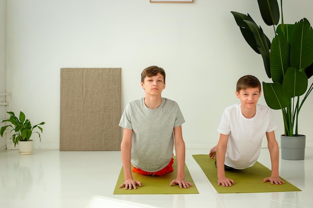 Dos lindos adolescentes realizan un ejercicio de yoga en colchonetas