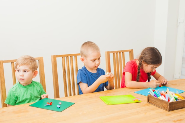 Dos lindos hermanito y hermana divirtiéndose junto con arcilla de modelado de colores en una guardería. Niños DIY con porcelana fría