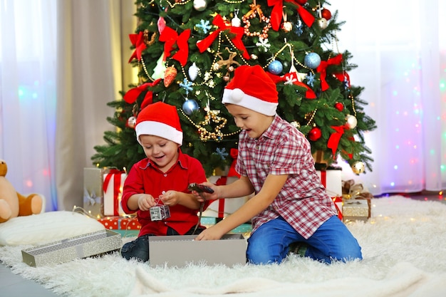 Dos lindos hermanos pequeños abriendo regalos en la decoración navideña