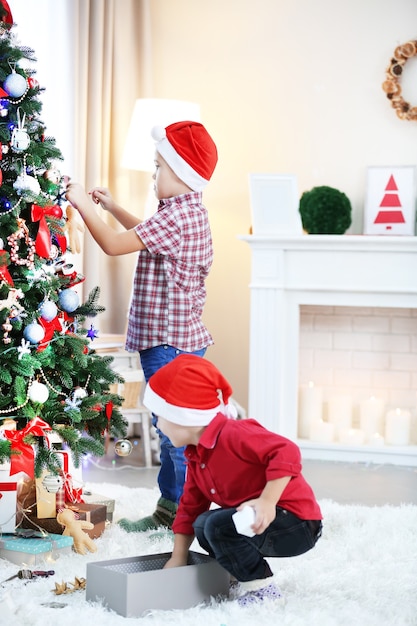 Dos lindos hermanos pequeños decorando el árbol de Navidad