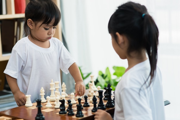 Dos lindos niños jugando al ajedrez en casa