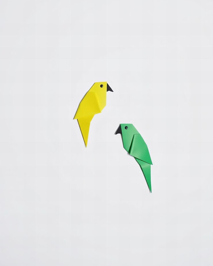 Foto dos loros origami simples de papel amarillo y verde aislados sobre un fondo blanco