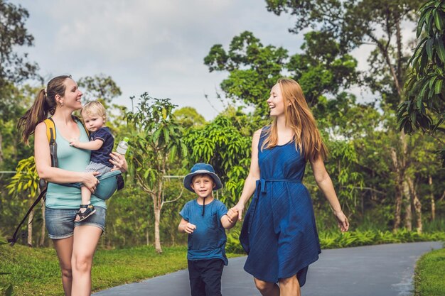 Dos madres y dos niños están caminando en el parque.