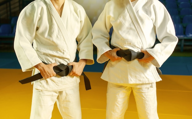 Dos maestros de deportes en judo con un kimano blanco con cinturón negro. Cortar Foto