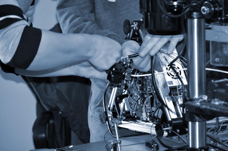 Foto dos maestros masculinos trabajan en el taller con impresora 3d de cables electrónicos
