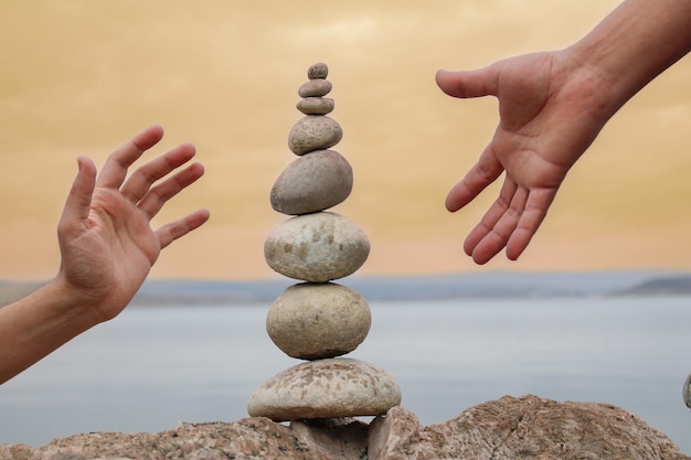 Foto dos manos alcanzando una pila de rocas con las palabras 'equilibrio'