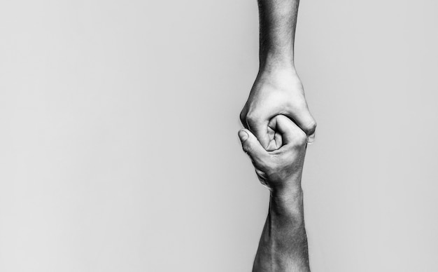 Dos manos, brazo de ayuda de un amigo, trabajo en equipo. Ayudar a la mano concepto y día internacional de la paz, apoyo. En blanco y negro.