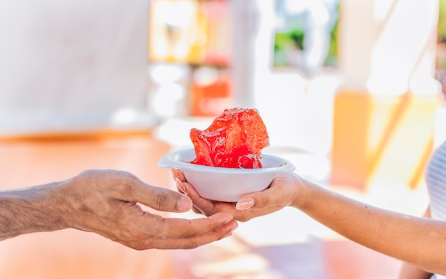 Dos manos compartiendo un raspado en la calle Primer plano de dos manos compartiendo una taza de raspado en la calle Concepto de raspados tradicionales nicaragüenses ICE SHAVING de Nagarote