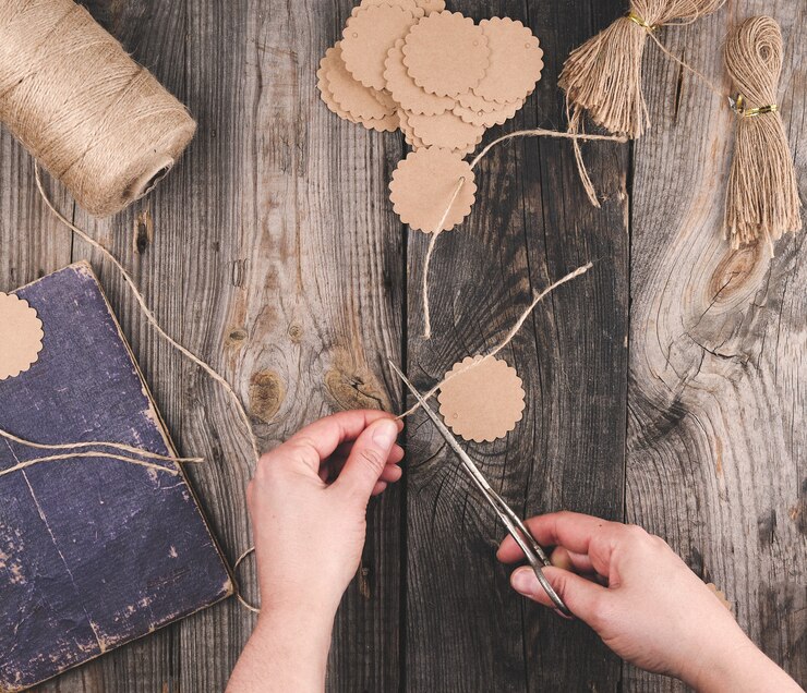 Foto dos manos femeninas y etiquetas de papel con una cuerda marrón en la mesa de madera gris