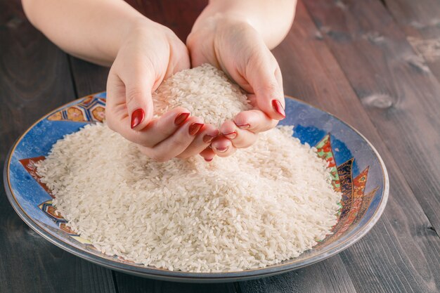 Dos manos con granos de arroz sobre plato