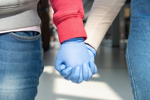 Dos manos en guantes de goma abrazados.