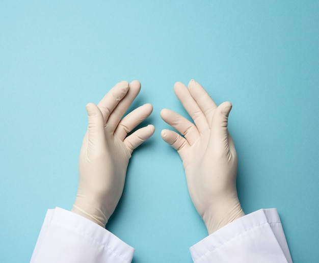 Dos manos masculinas en guantes de látex blancos, palmas del médico sobre un fondo azul, vista superior