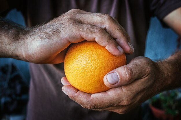 Dos manos masculinas sostienen una naranja.