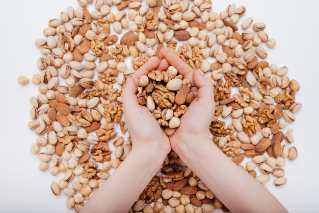 dos manos de un niño con surtido de frutos secos. nuez, pistacho, almendras, avellanas,