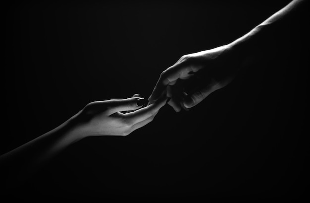 Foto dos manos que se extienden hacia la ternura tienden a tocarse manos en fondo negro toque romántico con