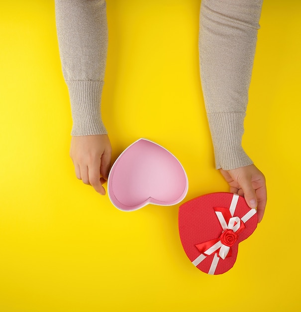 Dos manos sosteniendo una caja abierta en forma de corazón rojo