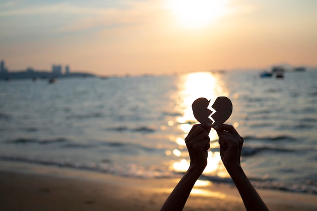 Dos manos sosteniendo en forma de corazón roto con el concepto de fondo de San Valentín de silueta de fondo al atardecer