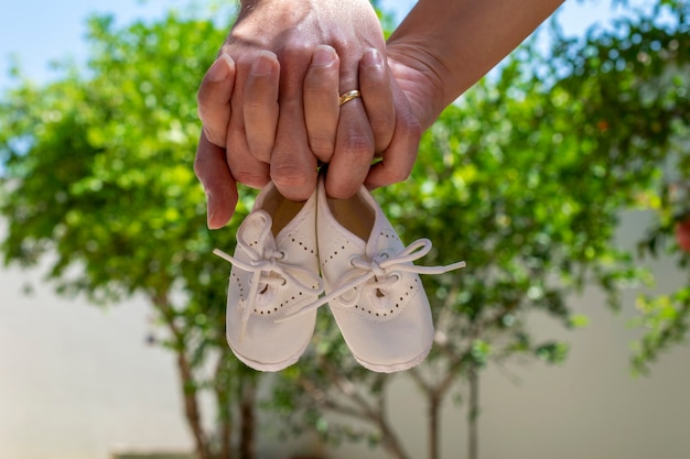 Dos manos sosteniendo zapatos de bebé. concepto de embarazo.