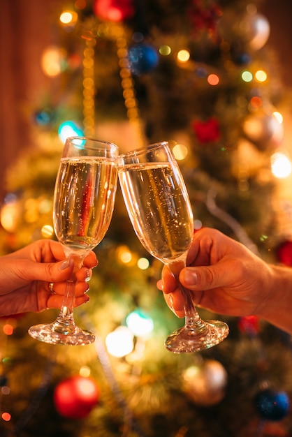 Dos manos tintinean vasos con champagne, navidad