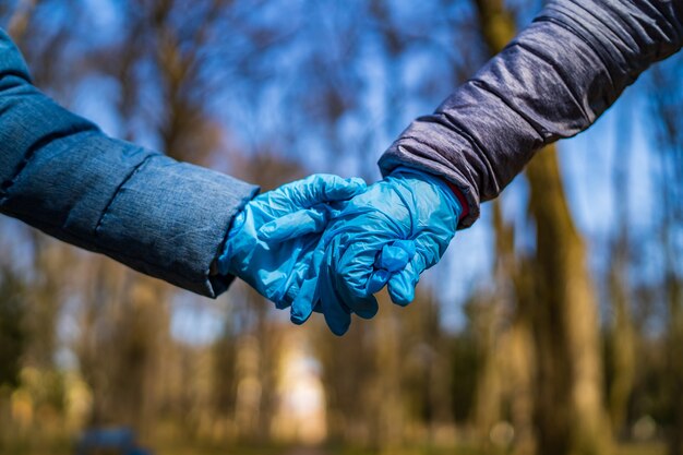 Dos manos tratando de abrazarse en el fondo del parque. El concepto de pandemia, cuarentena, prevención de virus, enfermedades.