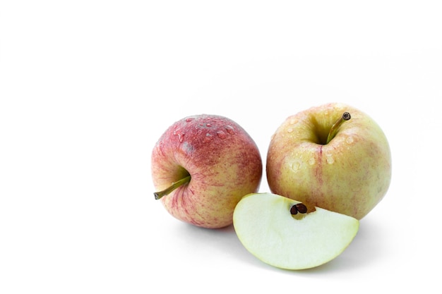 Dos manzanas aisladas con una rodaja de agua cae sobre un fondo blanco.