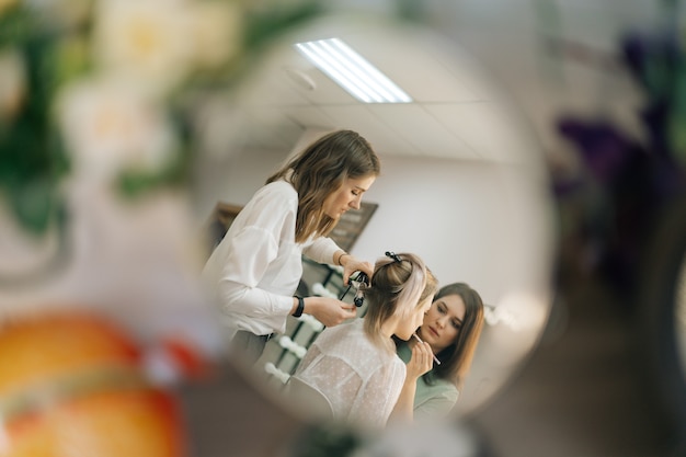 Dos maquilladora profesional femenina haciendo un cambio de imagen en el vestidor de iluminación