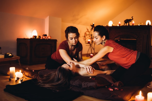 Dos masajistas haciendo masaje curativo, masaje en cuatro manos. Mujer disfrutando en relajante masaje en el tratamiento de spa de salud.