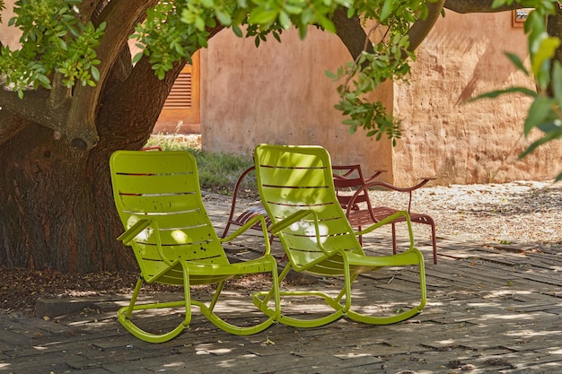 Dos mecedoras de patio vintage verdes debajo de un árbol sombreado en un jardín aislado y privado en casa Muebles de patio y juego de asientos para disfrutar y relajarse en verano Descansar y sentirse acogedor al aire libre