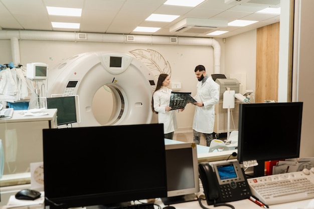 Foto dos médicos discutiendo los rayos x después de la tomografía computarizada del abdomen del paciente procedimiento de tomografía computarizada por tomografía computarizada para obtener imágenes internas detalladas del cuerpo e investigación sobre tumores en la cabeza, el cerebro y la columna vertebral