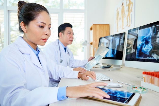 Dos médicos que trabajan con imágenes de rayos x en la mesa de la oficina
