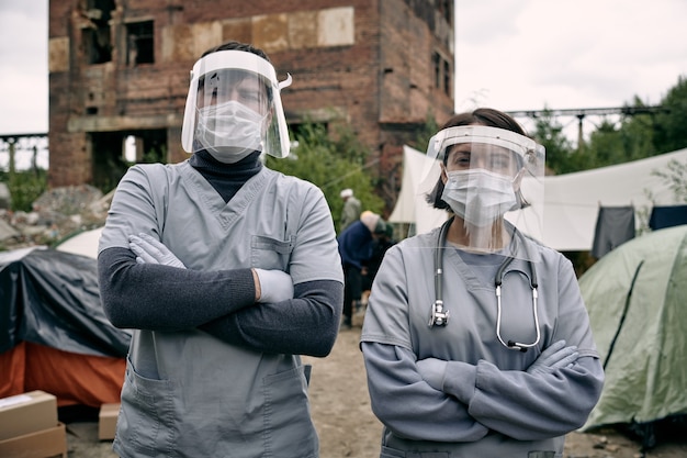 Dos médicos en ropa de trabajo protectora de pie en el campamento de refugiados