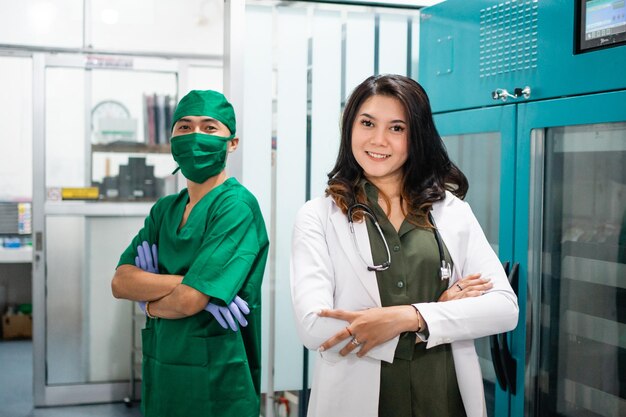 Foto dos médicos vestidos con uniformes blancos y verdes están de brazos cruzados en el hospital