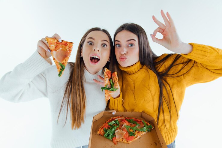 Dos mejores amigos comiendo pizza apetitosa. Chicas sonriendo, mirando a la cámara y posando.