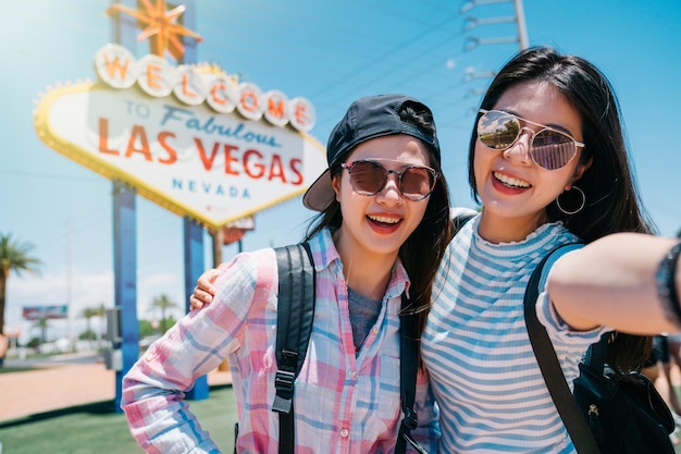 dos mejores amigos tomando selfie con la bienvenida al fabuloso cartel de Las Vegas en Estados Unidos. Concepto de amistad con jóvenes divirtiéndose juntos tomando una foto de autorretrato en las vacaciones de las vegas.