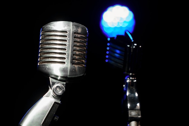 Dos micrófonos retro de metal en un soporte contra el fondo de la luz del concierto