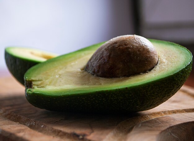 Dos mitades de aguacate fresco verde están sobre una tabla de madera.