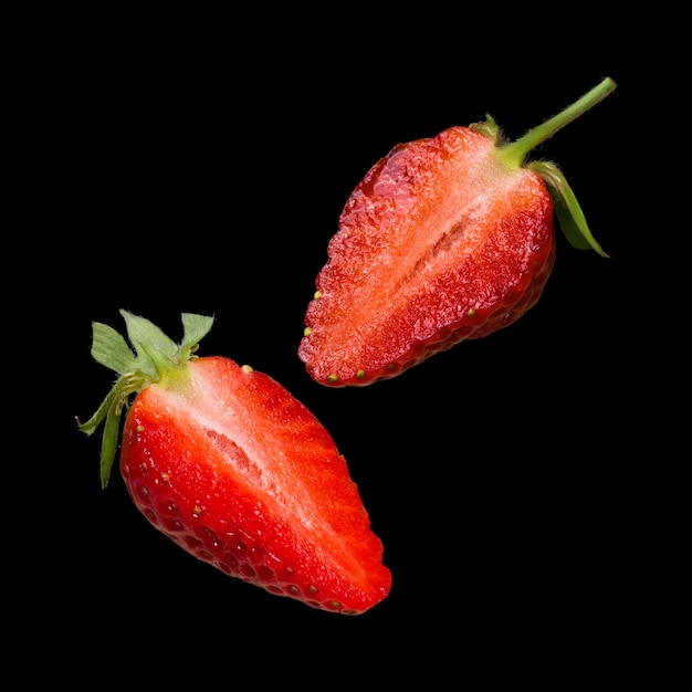 Dos mitades de fresa fresca madura aislado sobre fondo negro