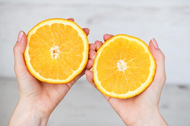 Dos mitades de naranja en manos femeninas