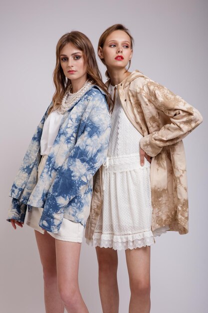 Dos modelos de alta costura en chaquetas con rayas azules y beige, vestido blanco, falda, camiseta, collar