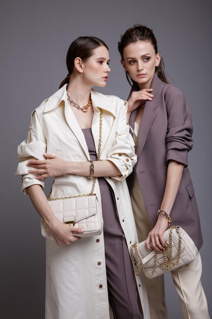 Dos modelos de alta moda en bata blanca, chaqueta morada, pantalones, accesorios, bolsos