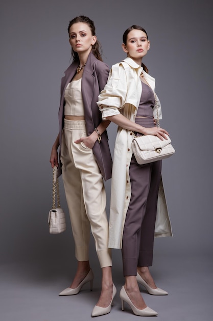 Dos modelos de alta moda en bata blanca, chaqueta morada, pantalones, accesorios, bolsos