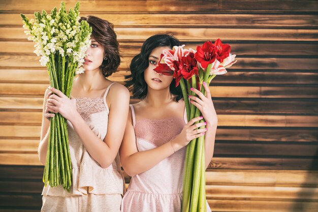 Dos modelos de chica joven y bella en ropa interior delicada con flores sobre fondo de madera